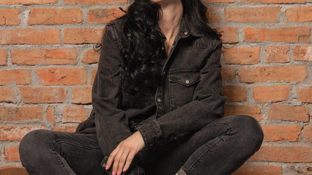 B бял домашен халат е вперила поглед в бившата сграда